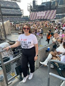 Hannah is at the Taylor Swift Eras Tour with the concert stage behind her. 